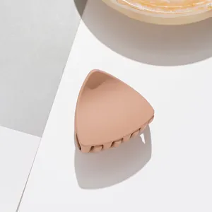 Detailed view of matte milk tea hair claw clip with geometric triangle design and soft shadows