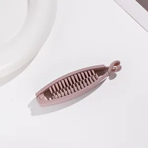 Détail d'une pince banane en résine vieux rose montrant les dents et le fermoir rotatif