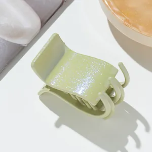 Détail d'une pince à cheveux vert avocat pailletée sur un plateau en ambre élégant