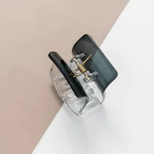 Detail view of transparent acrylic hair claw clip with gradient grey finish and gold spring