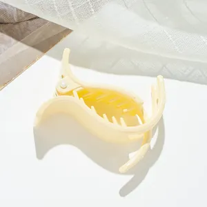 Detail of a creamy yellow small shark hair clip with a glossy finish for hair styling