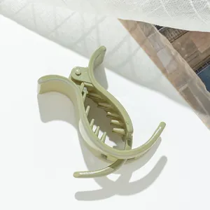 Close-up of a light green glittery hair claw clip with a glossy finish on white lace