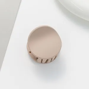 Macro detail of round matte hair claw clip in elegant beige finish for thin hair styling