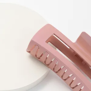 Detail of a large pearlescent pink claw clip with a glossy finish and hollow design