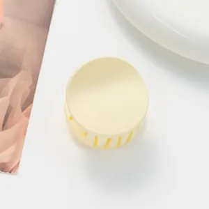 Macro shot of cream yellow matte hair claw clip with rounded design and internal teeth