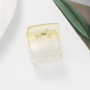 Macro shot of square transparent candy-colored hair claw with golden spring detail