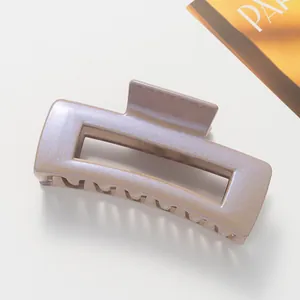 Macro view of pearlescent dusty pink rectangular hair claw clip with iridescent finish