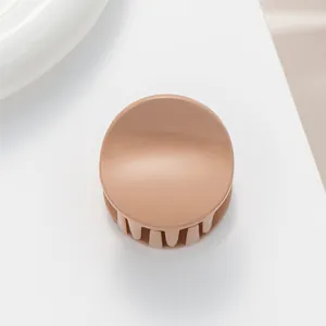 Close-up of a matte beige round hair claw clip with smooth texture and sturdy teeth