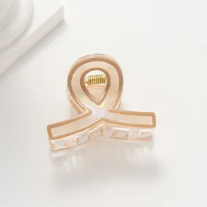 Dettaglio della pinza per capelli beige marmorizzata con bordo marrone e molla dorata