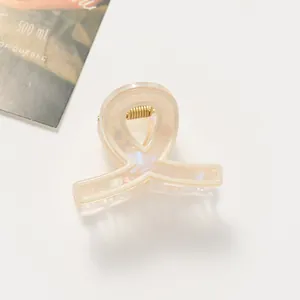 Vista dettagliata della clip per capelli a nastro color crema perlato con molla