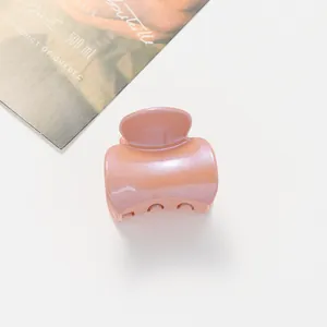 Détail d'une pince à cheveux rose abricot avec finition nacrée et dents arrondies