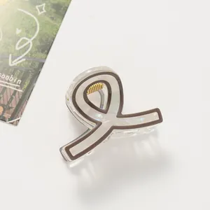 Dettaglio elegante molletta per capelli a nastro color crema con molla dorata su fondo bianco
