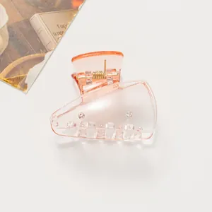 Détail d'une mini pince à cheveux rose pêche translucide avec mécanisme à ressort métallique