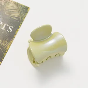 Détail d'une pince à cheveux vert clair pailletée avec finition nacrée sur fond blanc