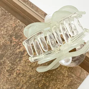 Eleganter großer lichtdurchlässiger grüner Haarklammer mit Perlen auf einem Holztablett