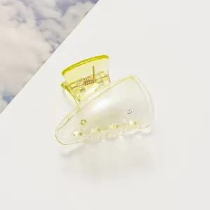 Détail d'une pince à cheveux jaune translucide de couleur bonbon au fini brillant
