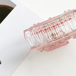 Detail view of transparent pink rectangular hair claw clip with sturdy metal spring