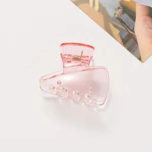 Détail d'une pince à cheveux rose translucide avec finition brillante sur fond blanc