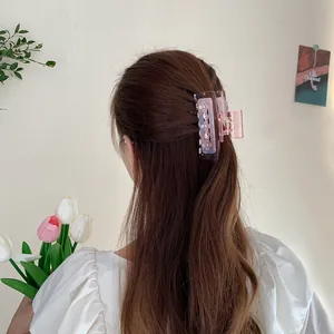 Iriserende roze klaver haarklem met strassteentjes gedragen op het haar van een vrouw