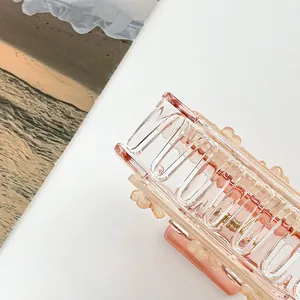 Makrodetail einer transparenten rosa rechteckigen Haarklammer mit einer Metallfeder