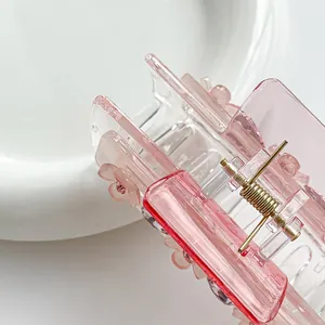 Roze doorschijnende klaver haarklem met strass bloemen op wit keramisch dienblad