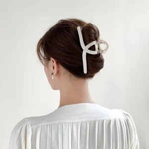 Rear view of model wearing a large cream plaid checkered shark hair clip for long hair