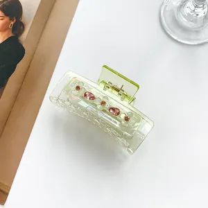Detail van de doorschijnende groene klaver haarklem met kleurrijke strassteentjes