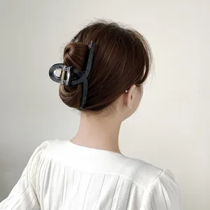 Macro detail of large black lattice shark clip securing hair on female model back view