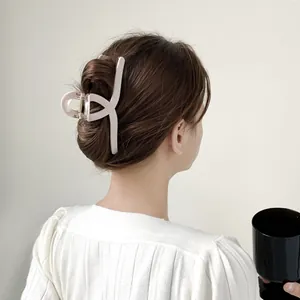 Detail of 13cm matte shark clip holding thick hair in a stylish updo on soft background