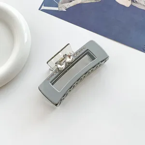 Détail d'une pince à cheveux grise rectangulaire avec strass en cœur et ressort métallique