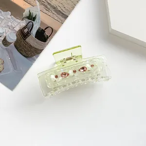 Details von hellgrüner rechteckiger Haarklammer mit weißen Blumen und rosa Strass