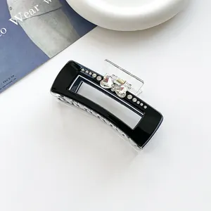 Détail d'une pince à cheveux cœur noire élégante avec strass et mécanisme à ressort métal