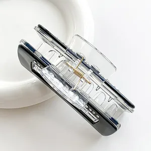 Square acrylic hair claw clip with rhinestones and gold metal spring on white bowl