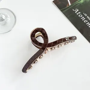 Detailed close-up of dark brown large shark hair clip with classic quilted diamond pattern