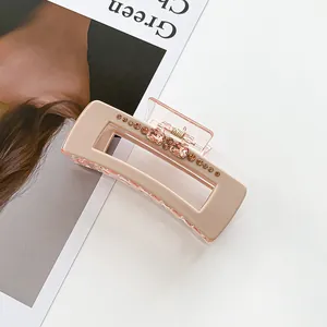 Detail of a square claw clip in beige resin with sparkling pink and brown rhinestones