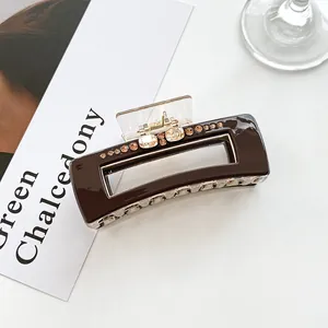 Macro detail of dark brown rectangular hair claw clip with sparkling champagne rhinestones