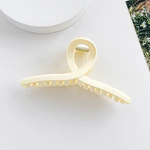 Détail d'une grande pince à cheveux mate crème avec un design croisé infini élégant