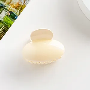 Gros plan d'une pince à cheveux ovale crème avec une finition brillante et ressort