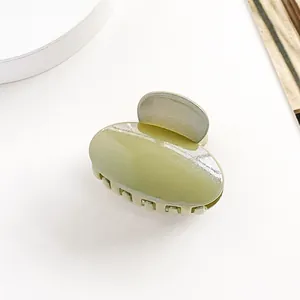 Gros plan sur la pince à cheveux ovale vert haricot en résine pailletée brillante