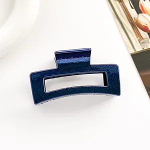 Détail de la pince à cheveux bleu foncé pailletée avec un design rectangulaire ajouré