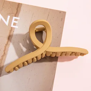 Gros plan sur une pince à cheveux mate jaune moutarde avec design croisé et fini texturé