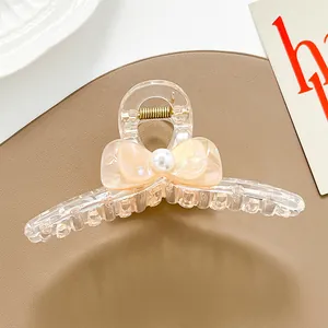 Primer plano de pinza para el pelo con lazo transparente champán, perla y muelle oro
