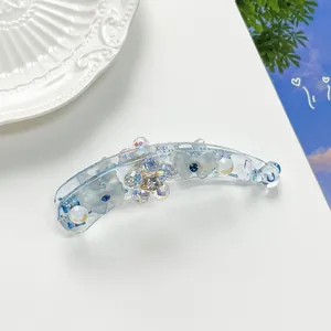 Détail de la pince à cheveux banane bleu clair avec fleurs en cristal et papillon
