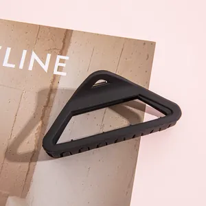 Détail d'une pince à cheveux triangle creuse noir mat sur fond de magazine rose