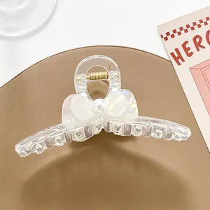 Detalle de pinza para el pelo transparente con lazo, perla y resorte dorado fuerte