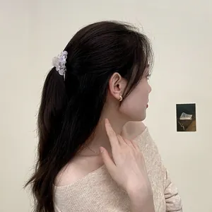 Modella indossa molletta per capelli in acetato rosa marmorizzato e orecchini a cerchio