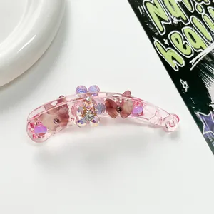 Gros plan sur la pince à cheveux banane rose avec fleurs irisées et détails papillon