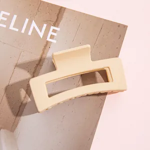 Vista detallada de una pinza para el cabello rectangular beige mate sobre fondo rosa