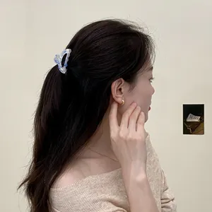 Mini molletta per capelli in acetato con motivo marmo blu indossata su una mezza coda