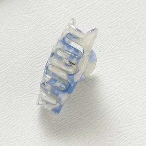 Dettaglio della molletta per capelli in acetato con motivo marmorizzato blu e bianco
